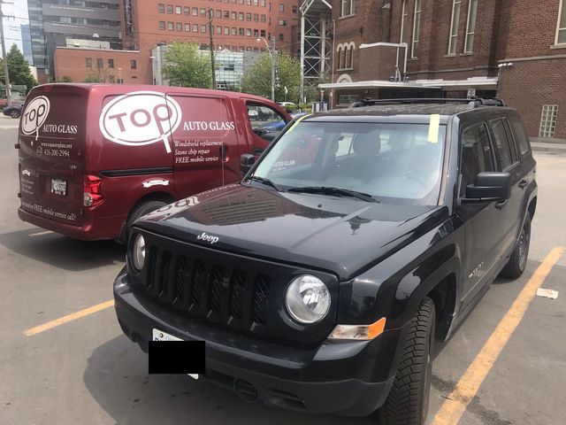 Black SUV with a new windshield next to a red Top Auto Glass van in a parking lot